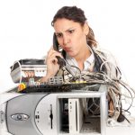 Woman on the phone looking confused at a broken computer