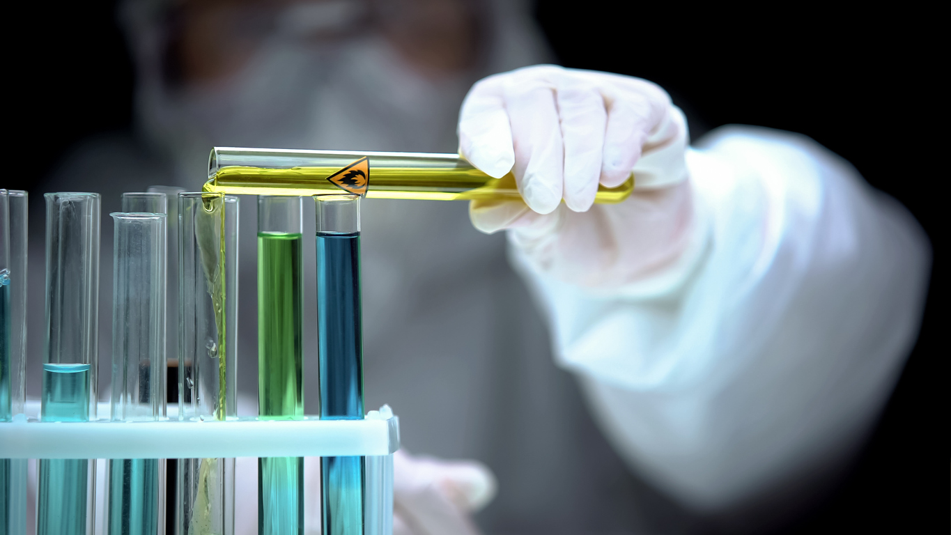 Researcher adding liquid from test tube with fire symbol, warning sign, danger